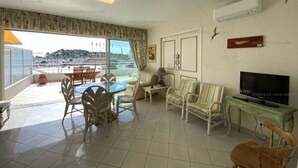 A living room with a balcony, a dining area, and a TV.