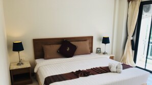 A hotel room with a large bed, two bedside tables, a nightstand, a window with curtains, and a view of the outdoors. - Global Hotel Beach View (Patong)