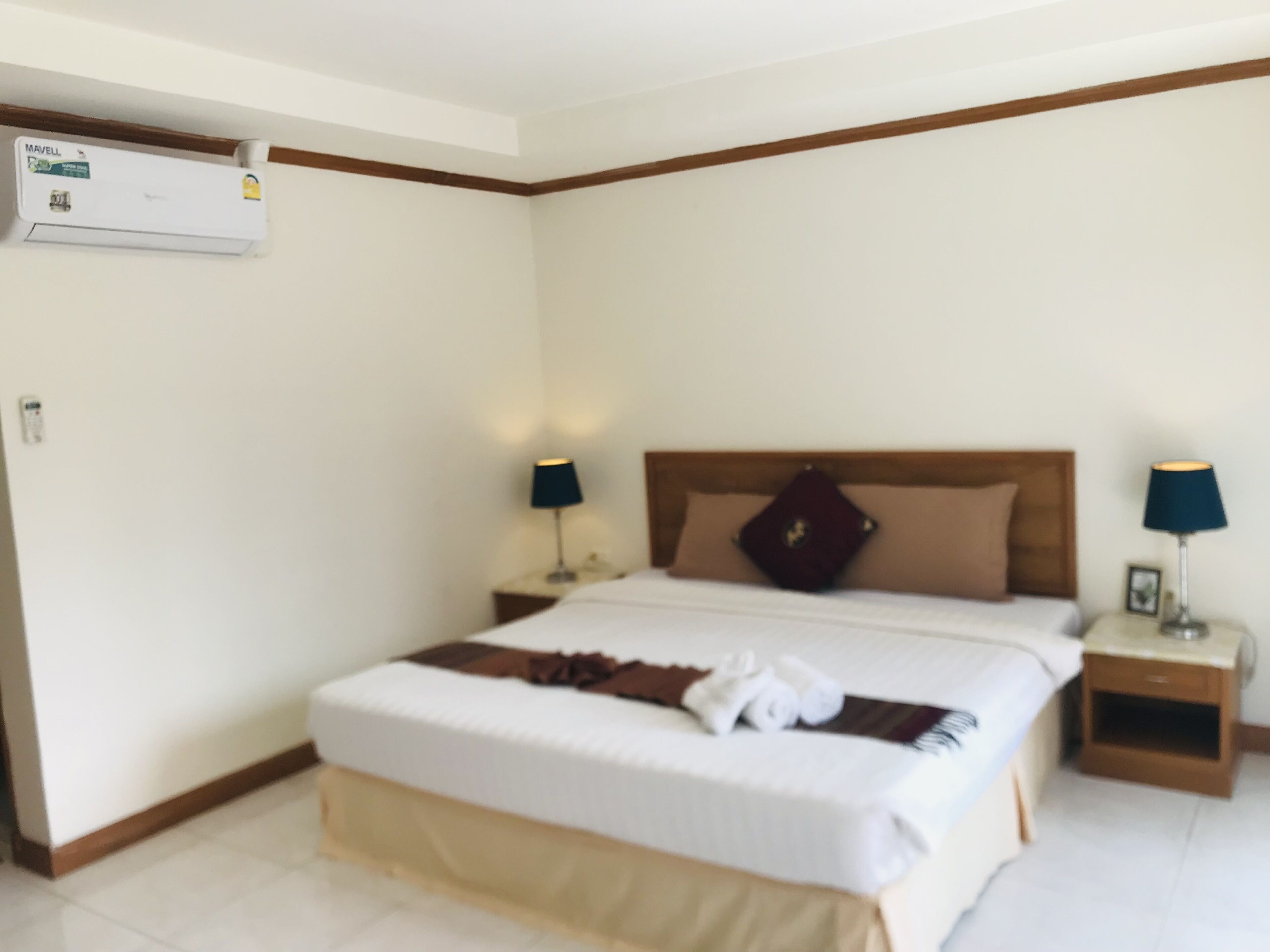 Una habitación de hotel con una cama, dos mesitas de noche, aire acondicionado y una ventana.