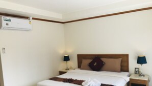 A hotel room with a bed, two bedside tables, a nightstand, a wall-mounted air conditioning unit, and a window. - Global Hotel Beach View (Patong)