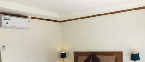Una habitación de hotel con una cama, dos mesitas de noche, aire acondicionado y una ventana.