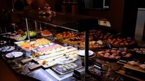 Un bufé con diversos alimentos, incluyendo ensaladas, pasteles y postres.