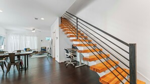 Un interior moderno con una escalera de madera, un comedor y un espacio de trabajo.