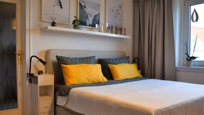 A neatly arranged bedroom with a bed, bedside tables, and a window with curtains. - Familienfreundliche Ferienwohnung in Wernigerode, mit Eigenem Garten (Wernigerode)