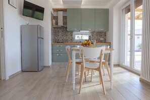 A modern kitchen with a built-in TV, a dining area with a table and chairs, and a large window providing natural light.