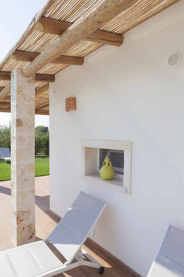 Une pièce avec un mur blanc, un plafond en bois et un vase jaune posé sur le rebord d’une fenêtre.
