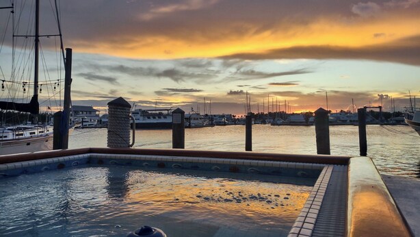 A hot tub with a view of a marina and boats during sunset.