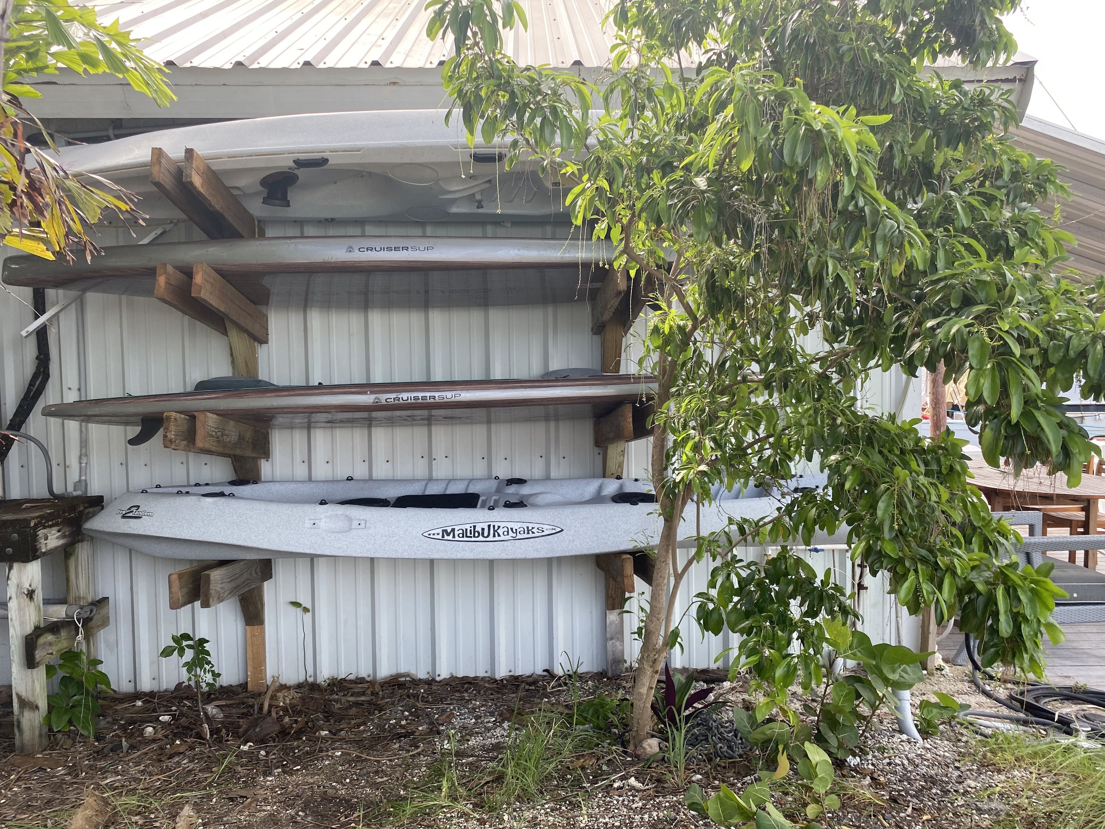 Ein überdachter Bootsstellplatz mit einem 'Cruisersup'-Kajak und einem 'Malibu Kayaks'-Kanu.