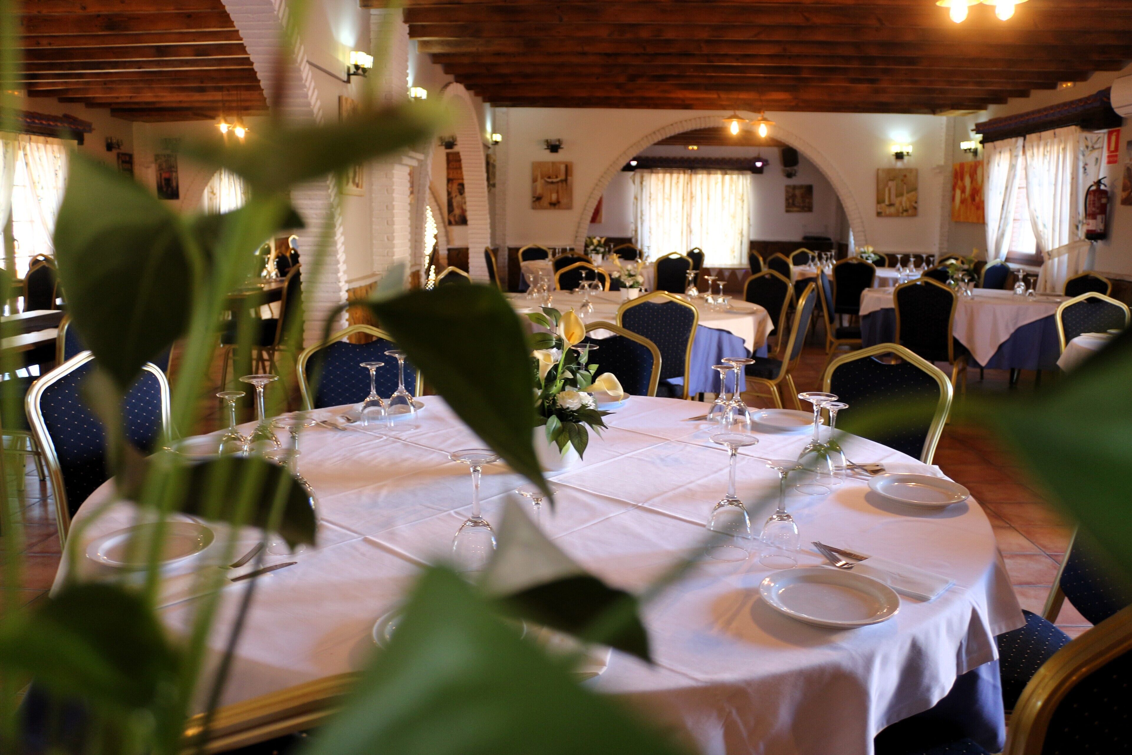 A restaurant with round tables set for dining, featuring white tablecloths and gold chairs.
