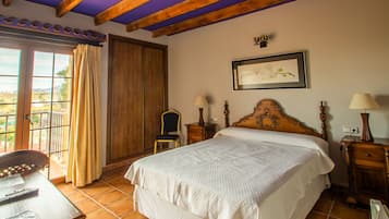 A bedroom with a bed, a chair, a nightstand, a lamp, a picture on the wall, and a window with curtains.
