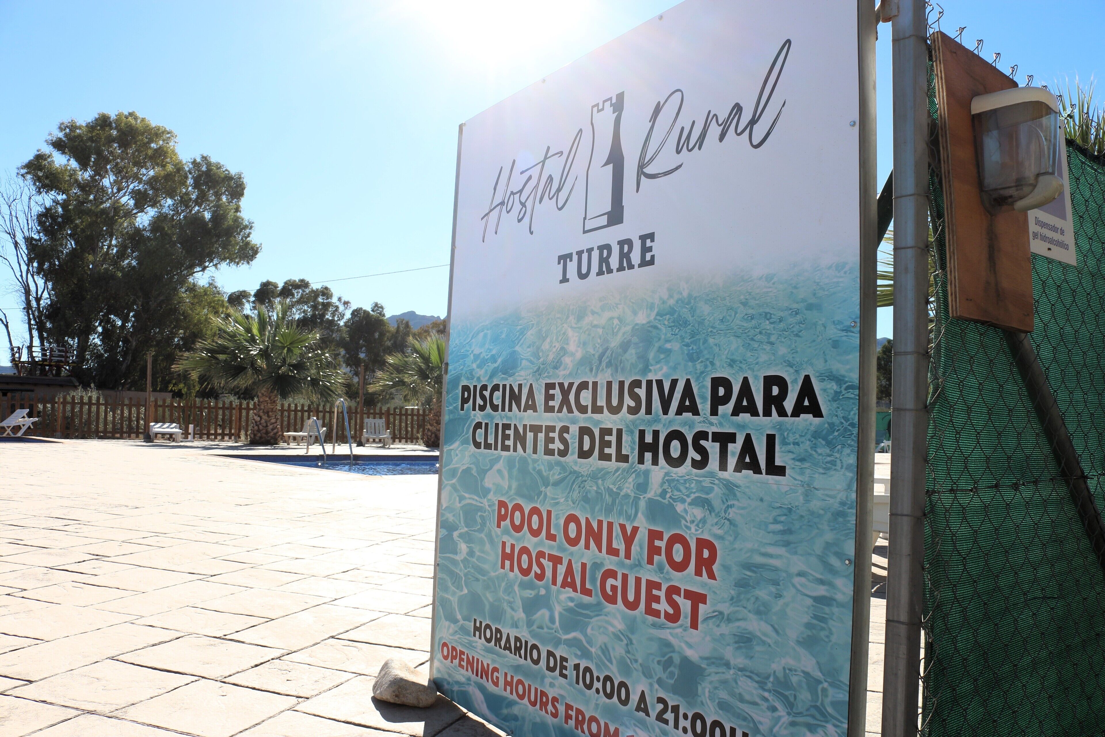 Naamplaatje voor hotel 'Hostal Rural Turre' met vermelding van een exclusief zwembad voor gasten, geopend van 10:00 tot 21:00.