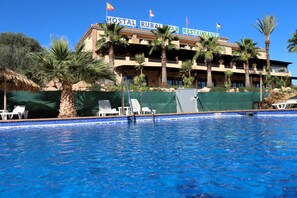 A hotel with a pool, palm trees, and a sign reading "HOSTAL RURAL TAR RESTAURANTE".