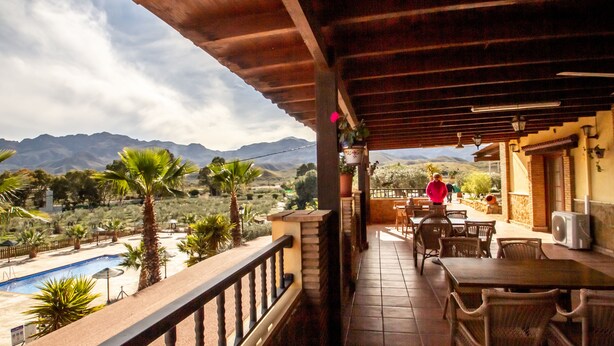 Un balcón con piscina, zona de comedor y vistas a la montaña.