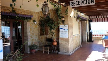 Un área de recepción con un letrero que indica piscina privada, pared de piedra, banco de madera y planta en maceta.