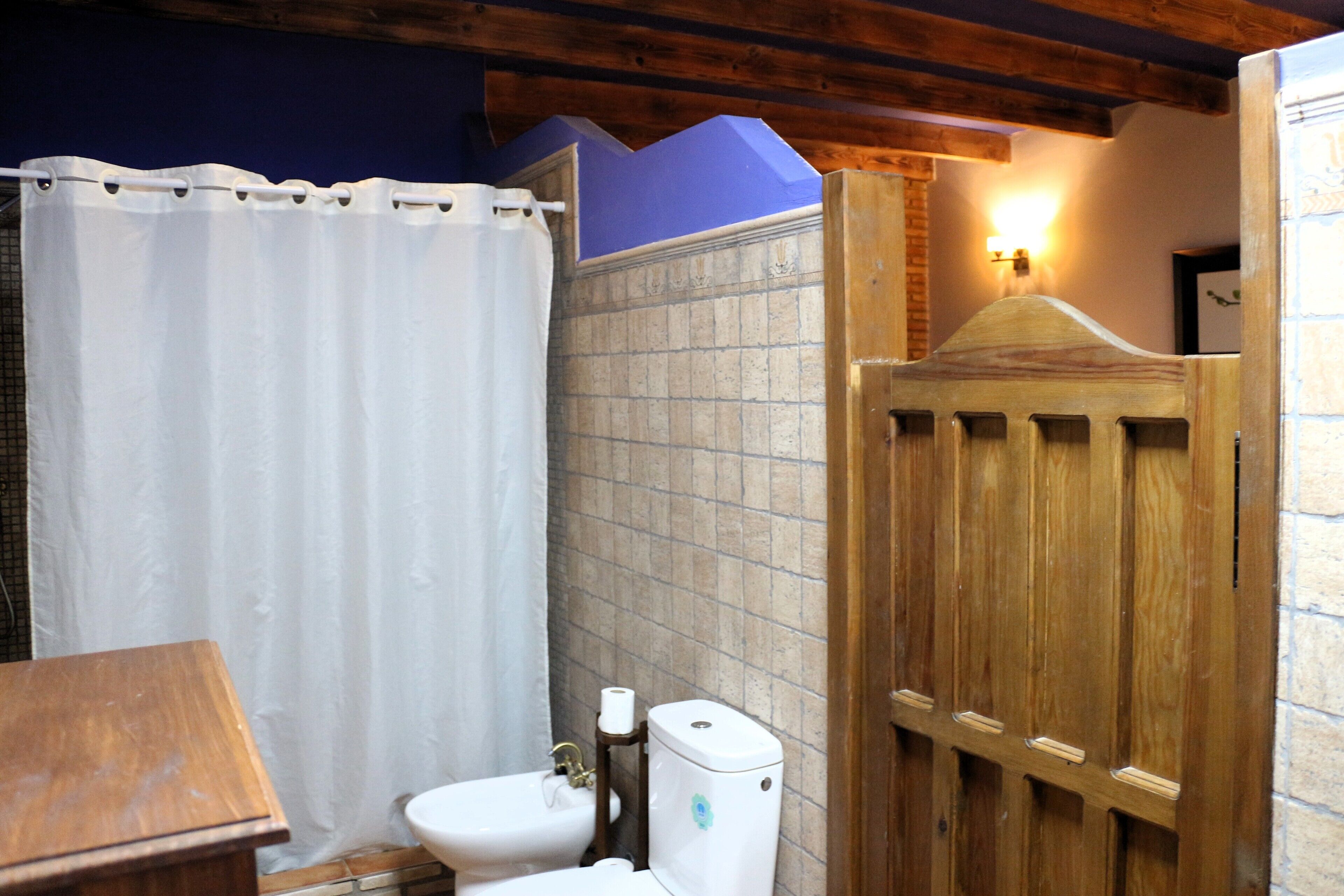 A bathroom with a wooden door, a white toilet, and a sink.