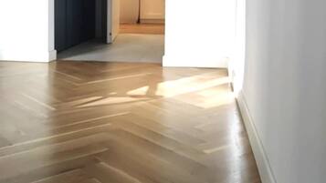 Un pasillo con piso de madera que conduce a una habitación con puerta blanca.
