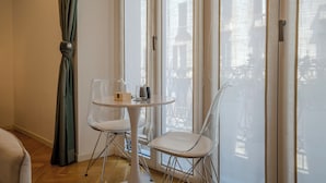 Une pièce moderne avec une table ronde et deux chaises, une vue dégagée grâce à de grandes fenêtres et un rideau vert.