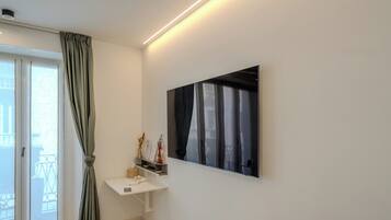 A modern room with a white desk, a large window with curtains, and a wall-mounted artwork.