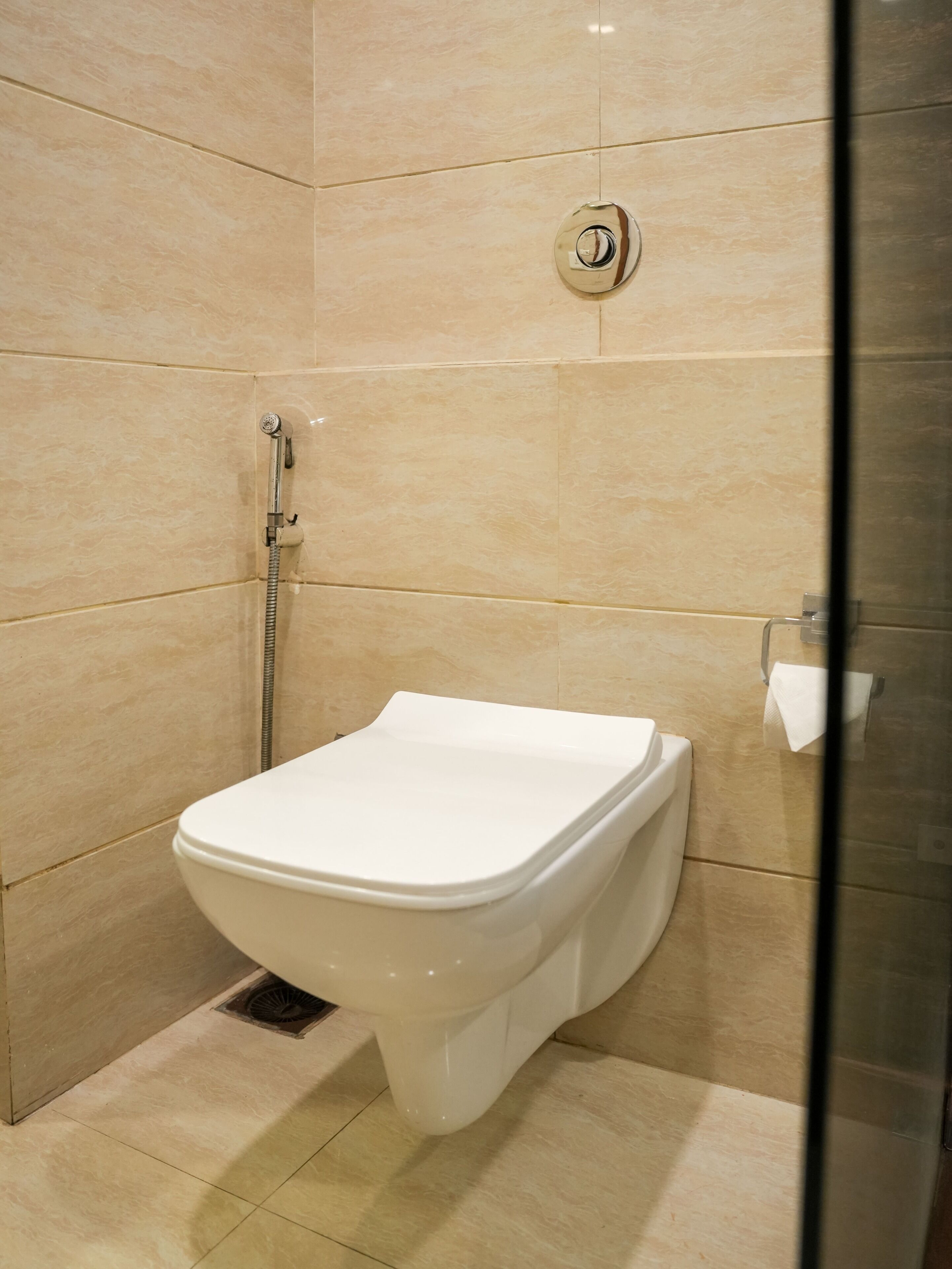 Een moderne badkamer met een wit toilet, een douche met een handdouche en een glazen douchewand.