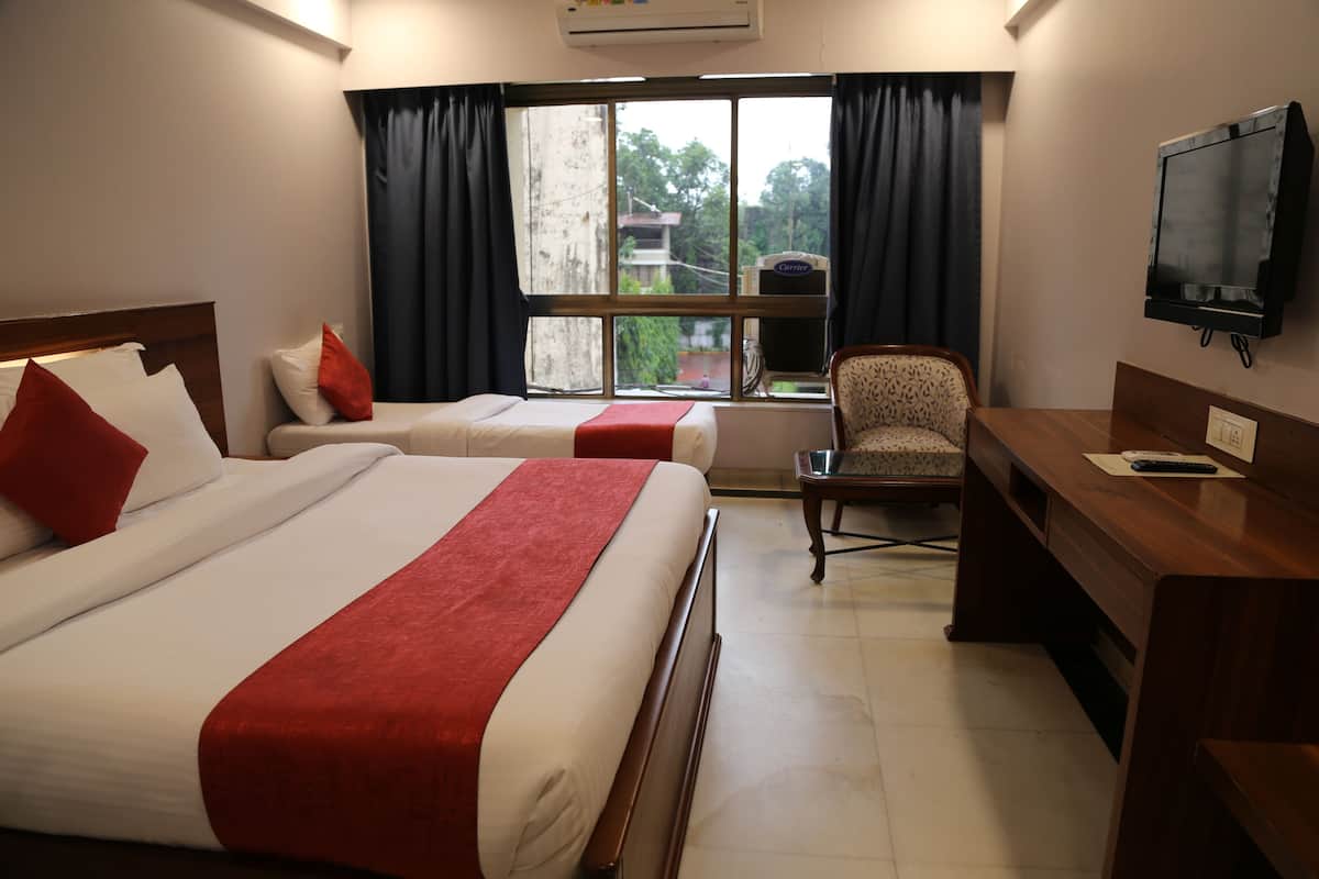 A hotel room with two beds, a desk, a chair, a TV, and a window with curtains.