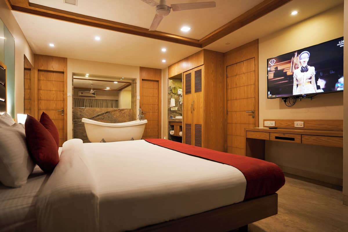 A modern hotel room with a large bed, a television mounted on the wall, and a wooden wardrobe.