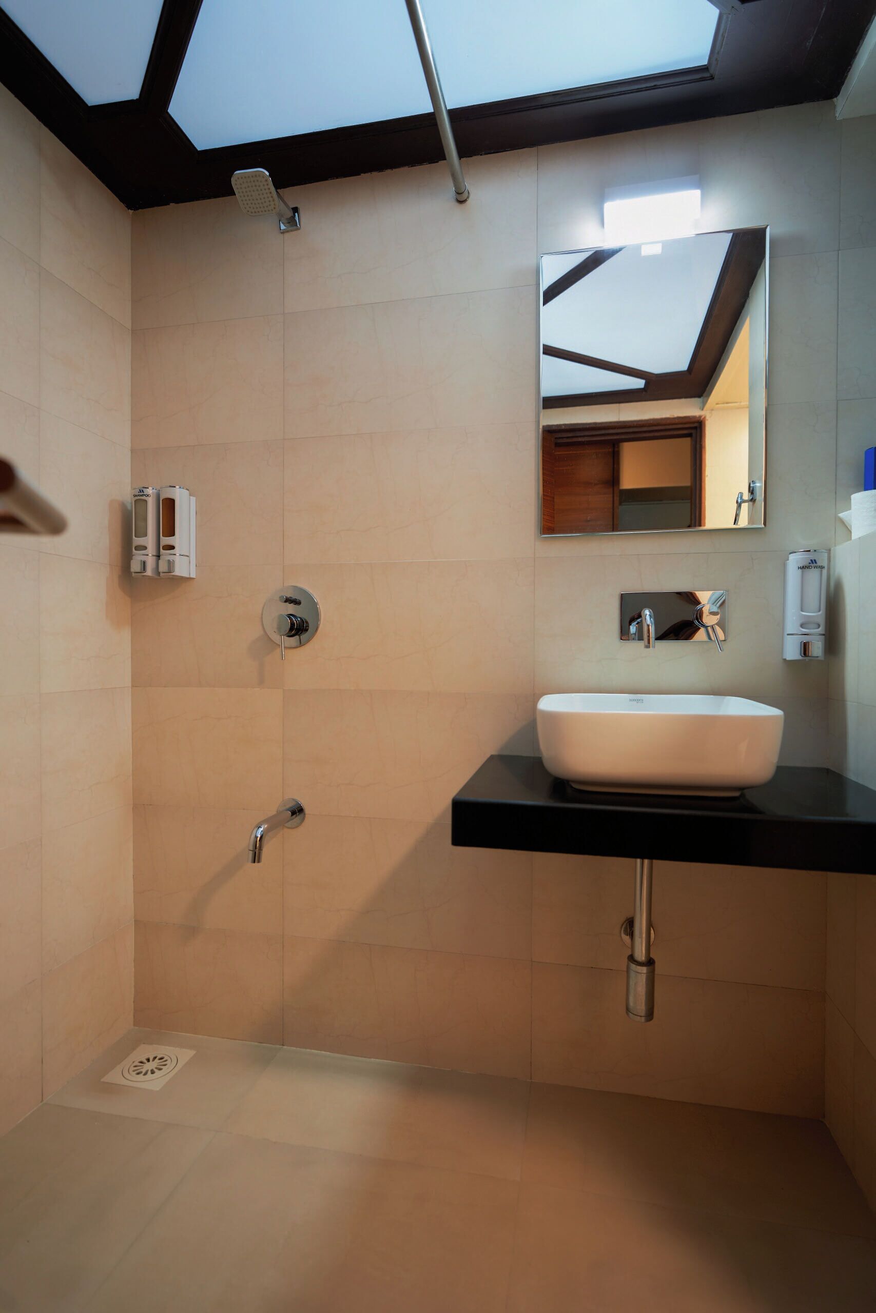 A modern bathroom with a skylight, a white sink, and a mirror.