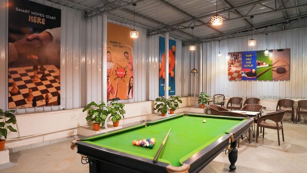 A billiards room with a pool table, potted plants, and posters on the walls. - The Metropole by Keyboard Hotels (Mawal)