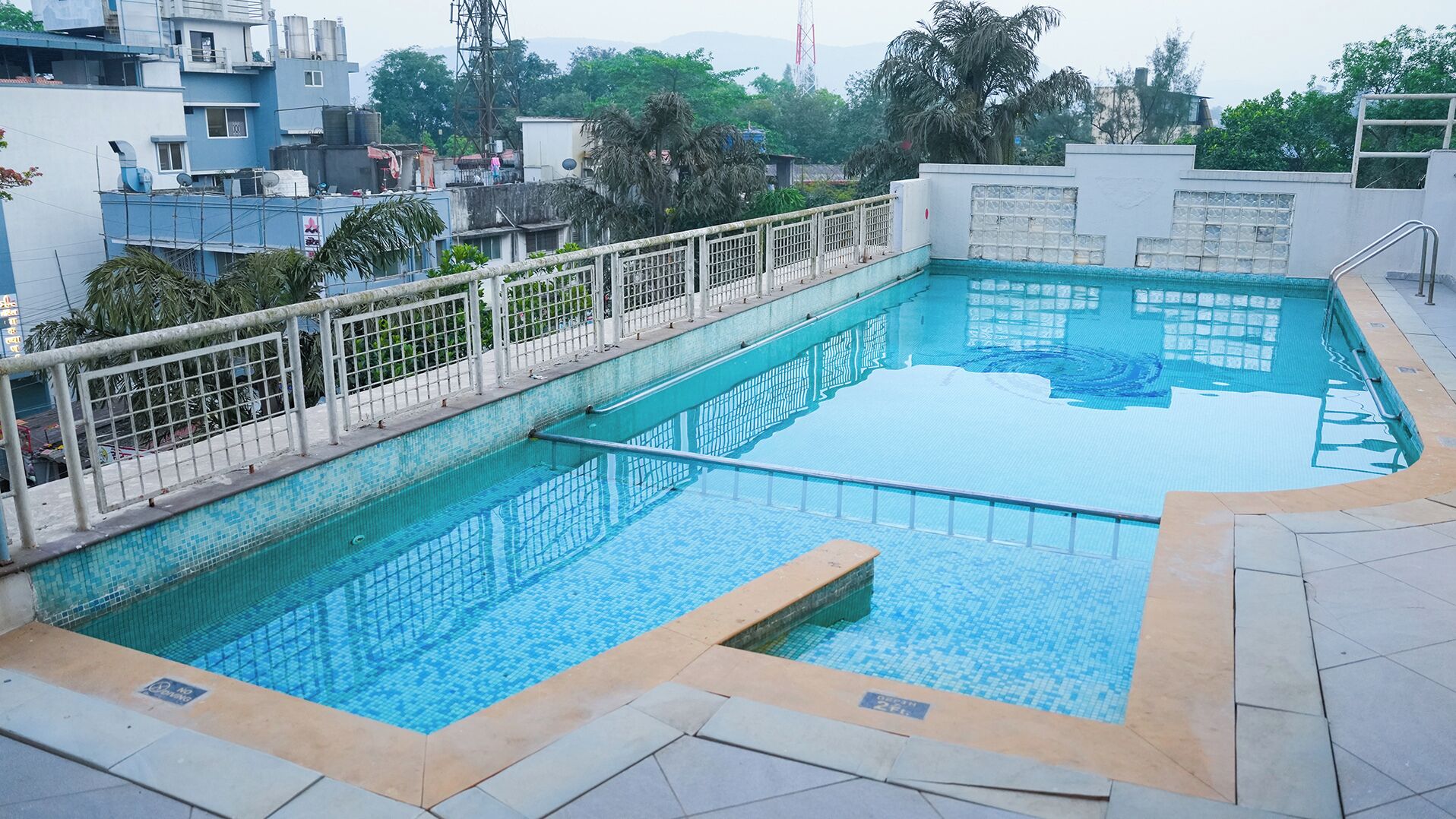 A rooftop swimming pool with a tiled edge and a metal railing.