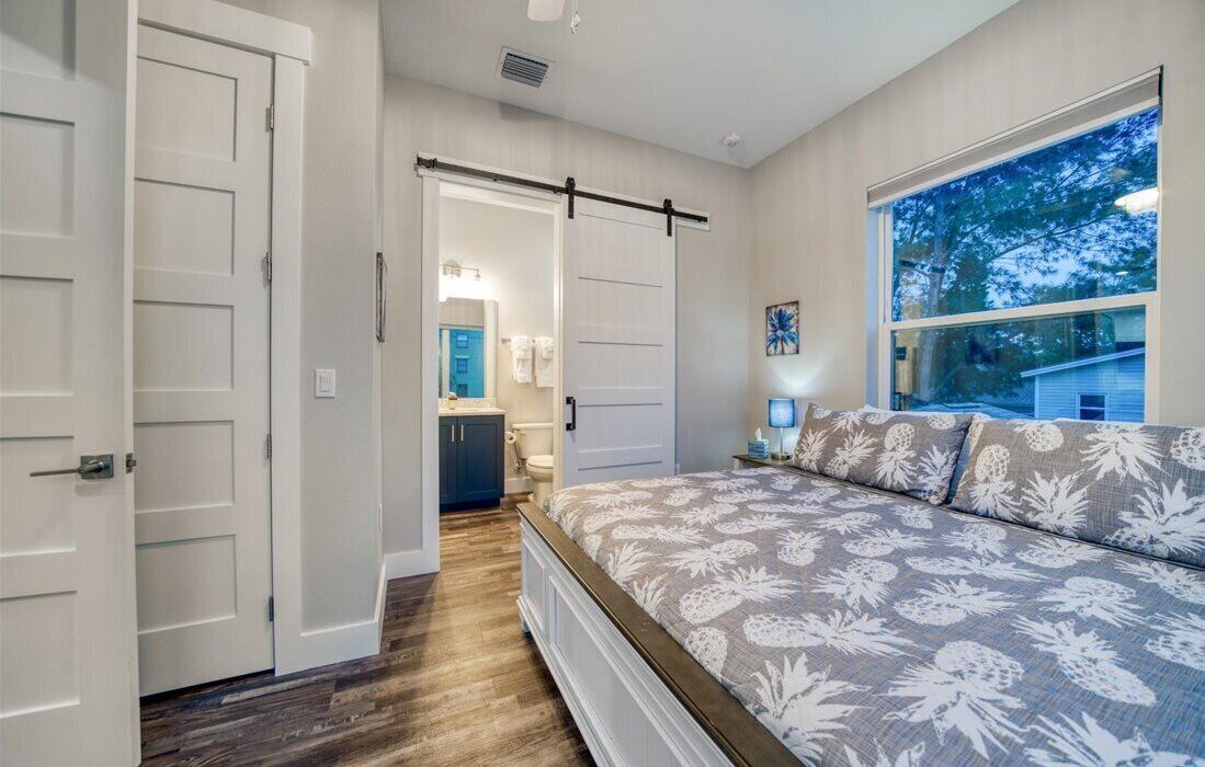 A bedroom with a large bed, a sliding door closet, and a view of the outdoors through a window.