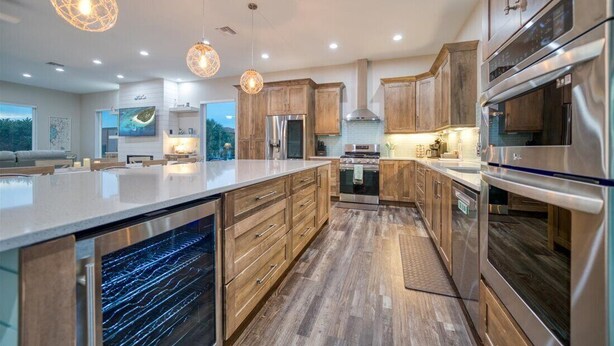 Una cocina moderna con armarios de madera, electrodomésticos de acero inoxidable e iluminación colgante.