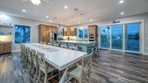 Una cocina amplia con una isla grande, armarios de madera e iluminación colgante.