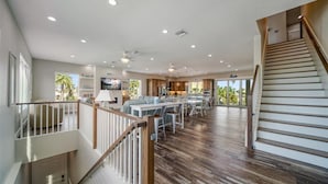 A spacious living area with a wooden staircase, a dining area, and a kitchen.
