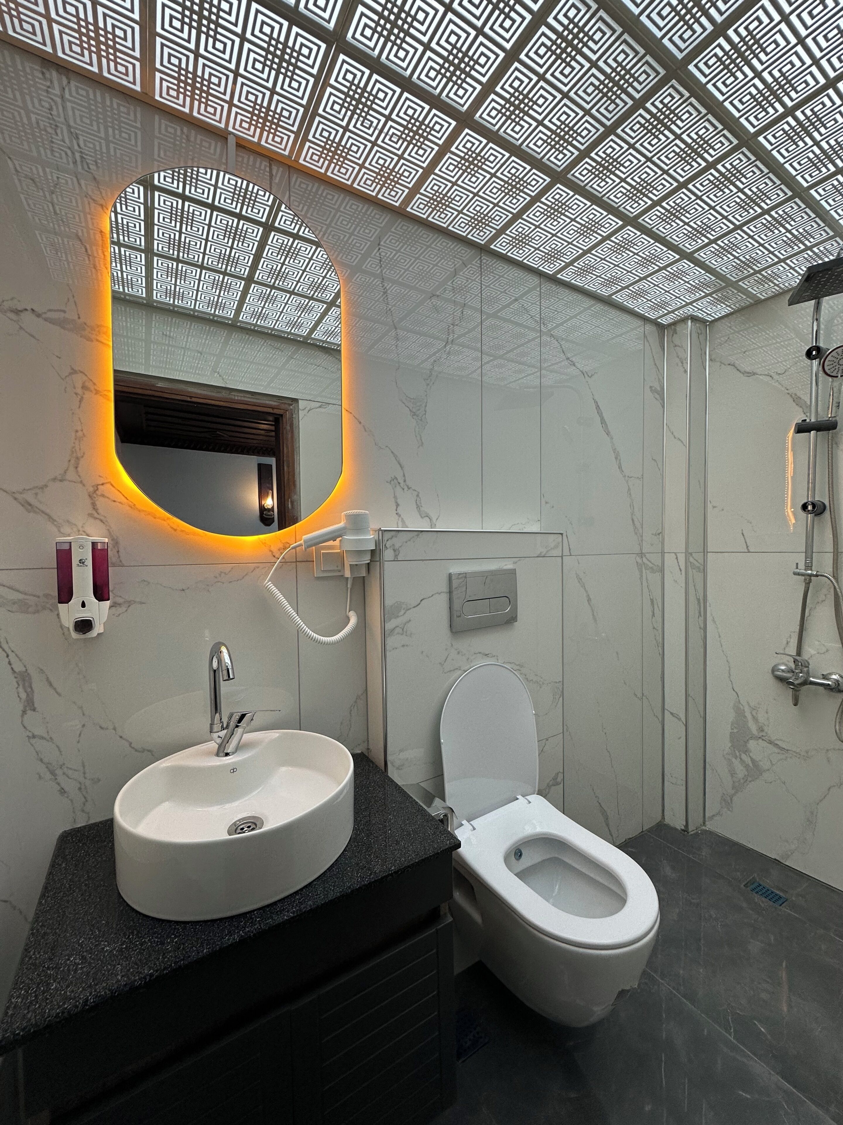 Un baño con lavamanos de mármol, inodoro y ducha.