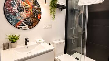 Un baño moderno con lavamanos, inodoro y cabina de ducha de vidrio.