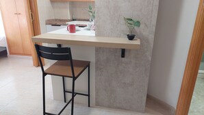 A small kitchen area with a countertop, a chair, a potted plant, and a red mug. - RESIDENCIAL ALCOY (Alcoy)