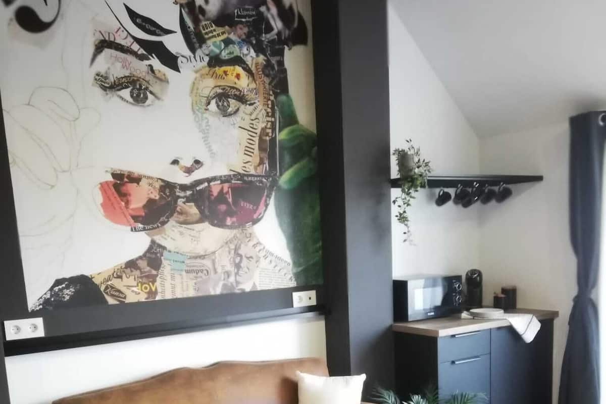 Ett modernt vardagsrum med en brun lädersoffa, två svarta soffbord och en stor abstrakt målning på väggen.