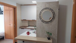 A modern bathroom with a wooden vanity, a large mirror, and a small potted plant. - RESIDENCIAL ALCOY (Alcoy)