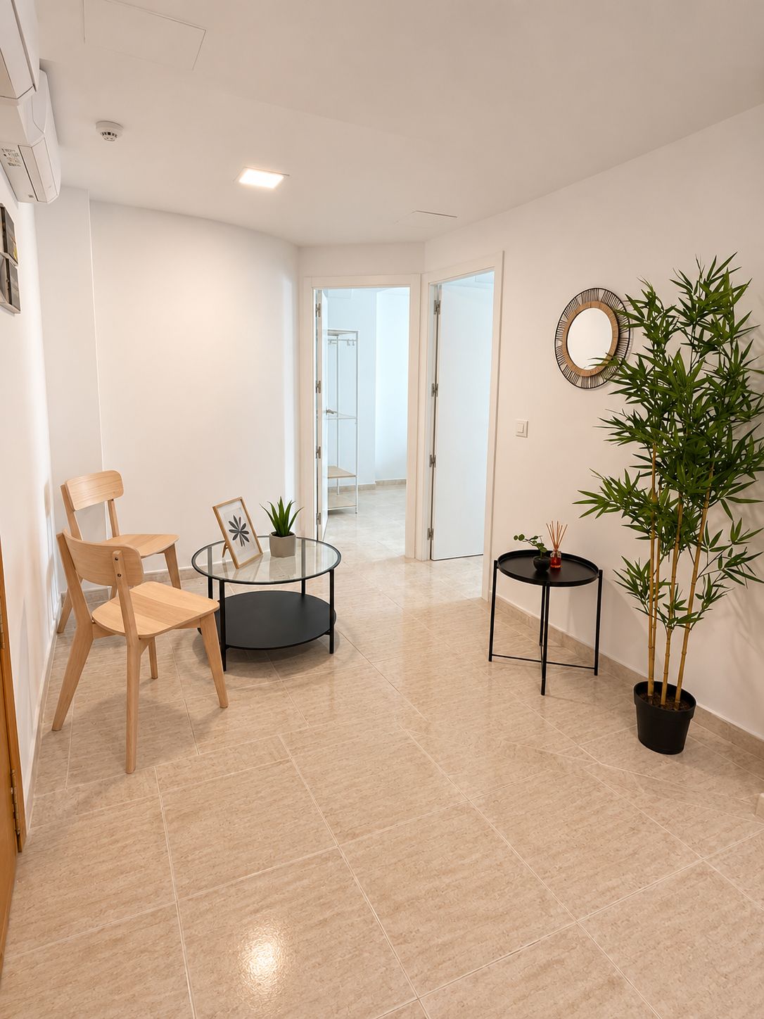 Una habitación amplia con una silla de madera, una mesita redonda y una planta en maceta.