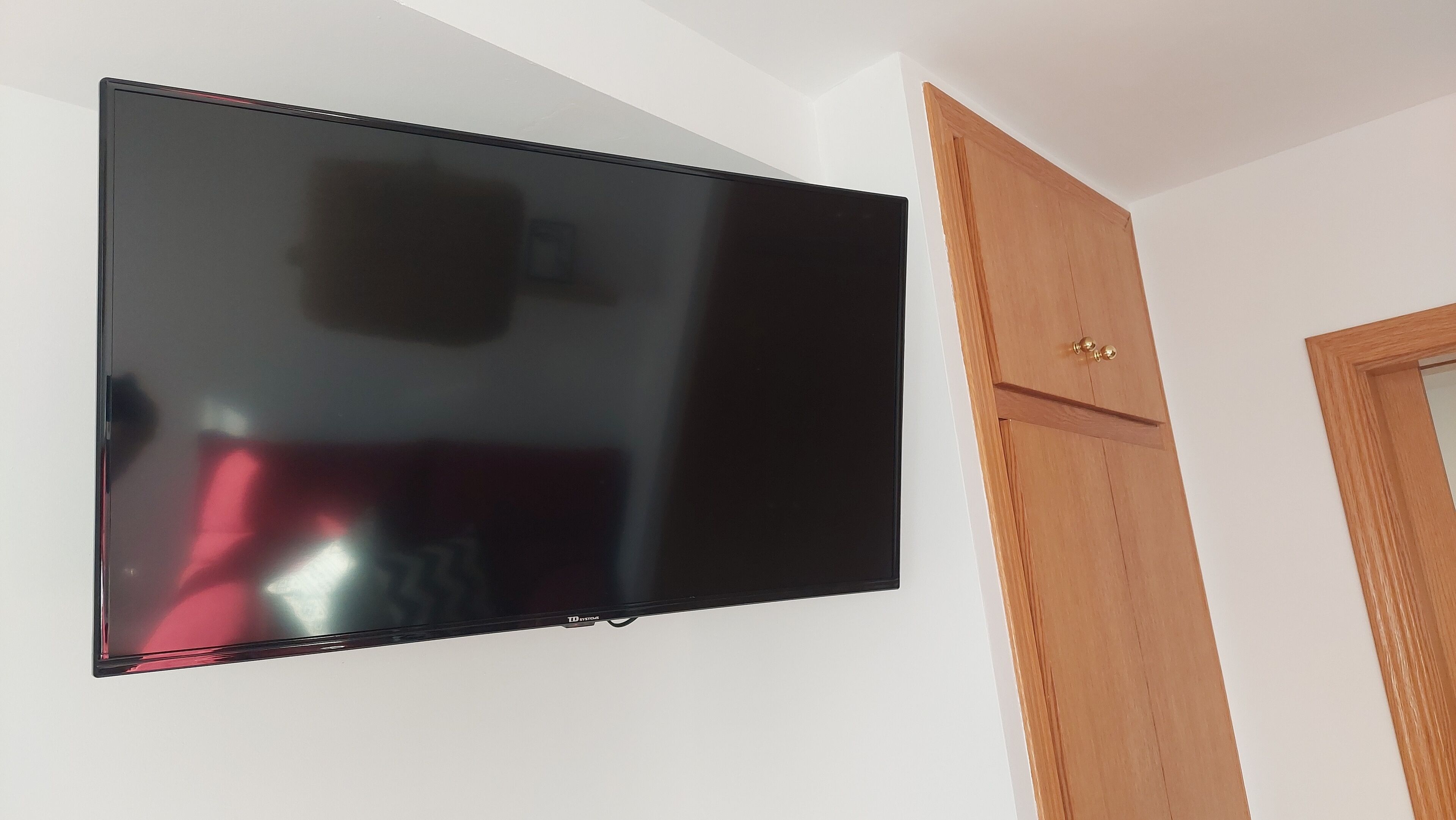 Televisor de pantalla plana montado en una pared blanca.