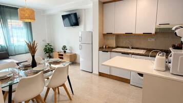 Cuina moderna amb armaris blancs, forn integrat i microones.