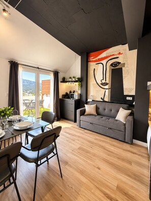 A modern living space with a dining area, a sofa, and a kitchen. - RESIDENCIAL ALCOY (Alcoy)
