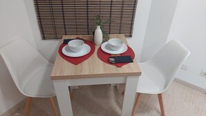A dining table with two white chairs, a vase with green plants, and a red placemat. - RESIDENCIAL ALCOY (Alcoy)