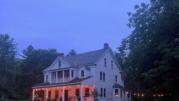 A large, two-story house with a porch and string lights.