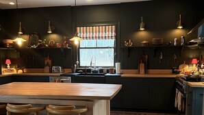 A modern kitchen with a wooden island, dark cabinetry, and pendant lighting.