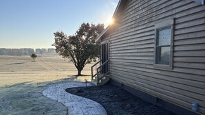 A single-story house with a sloped roof, a front porch, and a small tree in the yard. - Serenity Gardens located in the Rolling Hills of Appalachia Ohio (Albany)