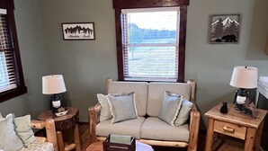 A cozy living room with a sofa, two armchairs, a coffee table, and a rug with animal prints. - Serenity Gardens located in the Rolling Hills of Appalachia Ohio (Albany)