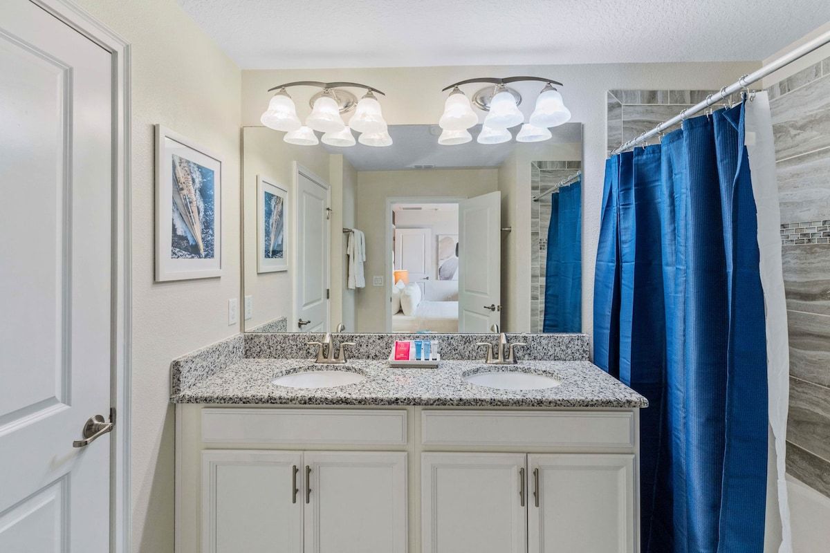 Sleek and Modern Oasis: Step into a sleek and modern oasis in our bathroom, complete with a vanity mirror, two sinks, and a luxurious walk-in shower-tub for your ultimate relaxation.