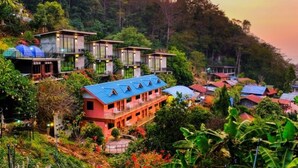 A hillside hotel with multiple buildings, each featuring balconies and large windows. - Baan Rabiengfah resort (Wiang Kaen)