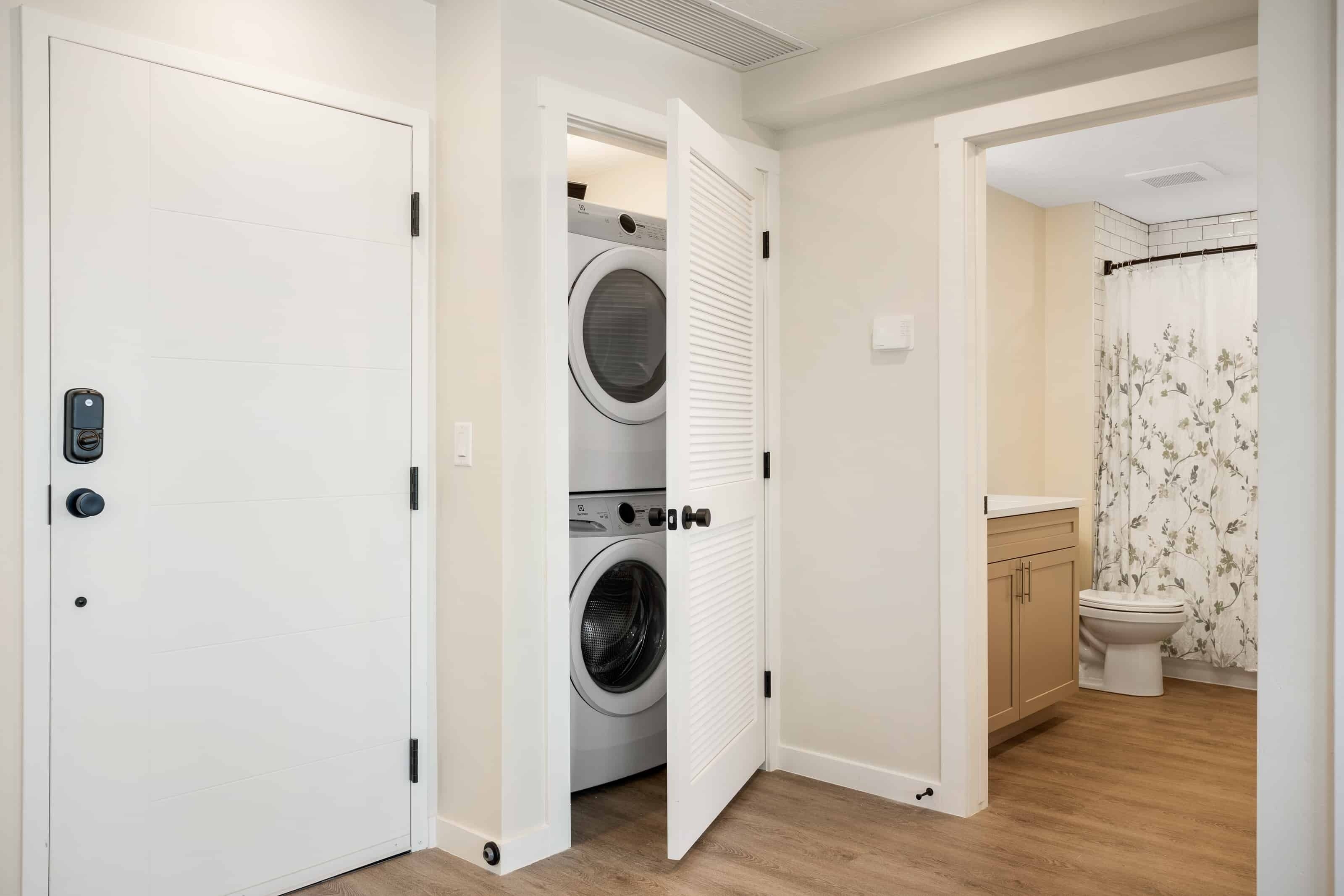 A laundry room with a washing machine and dryer, a toilet, and a shower area.