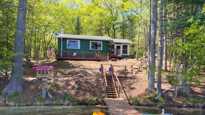 A cabin with a dock, kayaks, and a small boat.